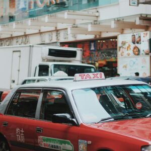 Black taxi parked in front of illuminated West End theatre marquee