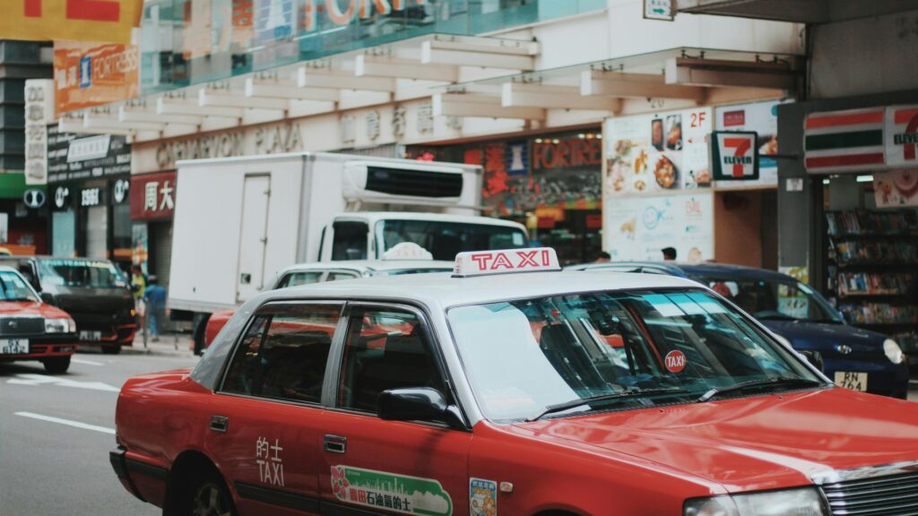 Black taxi parked in front of illuminated West End theatre marquee