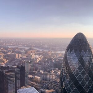 Aerial view of London's financial district featuring the iconic Gherkin building and modern skyscrapers during sunset