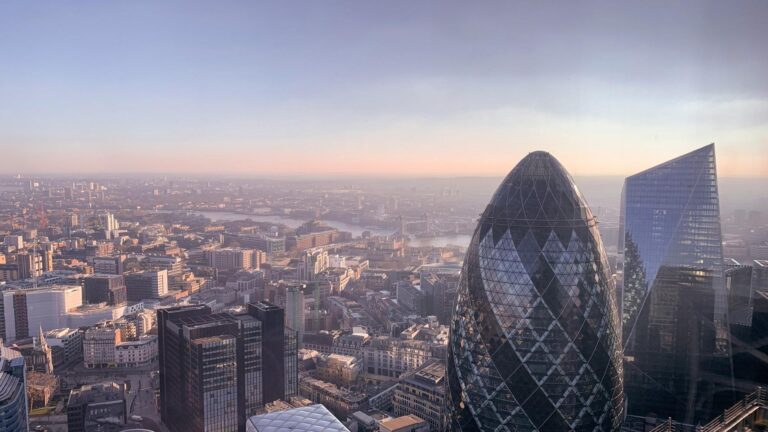 Aerial view of London's financial district featuring the iconic Gherkin building and modern skyscrapers during sunset