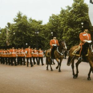 British Royal Guards in traditional red uniforms marching with mounted officers during ceremonial parade