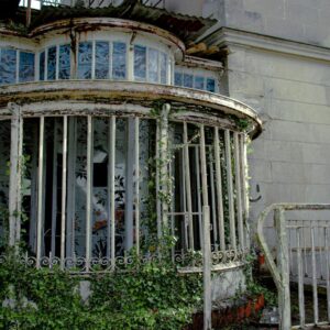 Rusty and overgrown conservatory with barred windows