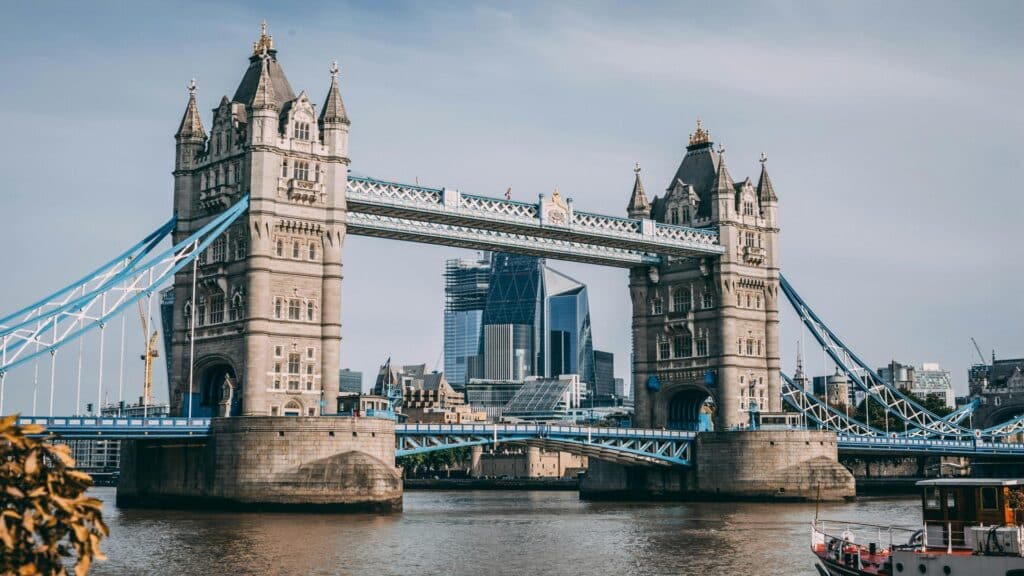 Tower Bridge in London with a boat on River Thames, modern city skyline in background