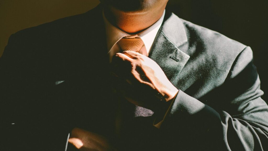 Professional businessman adjusting tie in formal grey suit