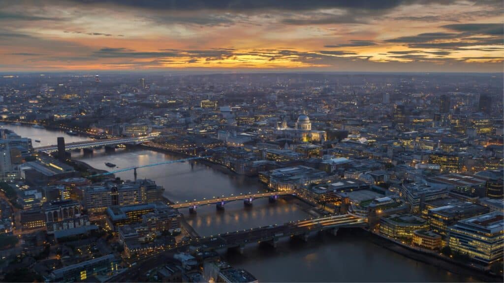 Aerial view of London at sunset showing the River Thames, St Paul's Cathedral, and illuminated bridges with potential water taxi routes