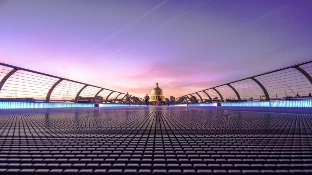 View of St Paul's Cathedral from Millennium Bridge with purple sunset sky and illuminated walkway