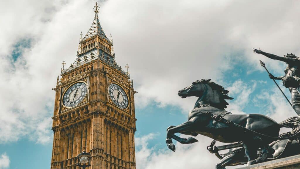 View of Big Ben clock tower with Boadicea chariot statue silhouette against cloudy blue sky