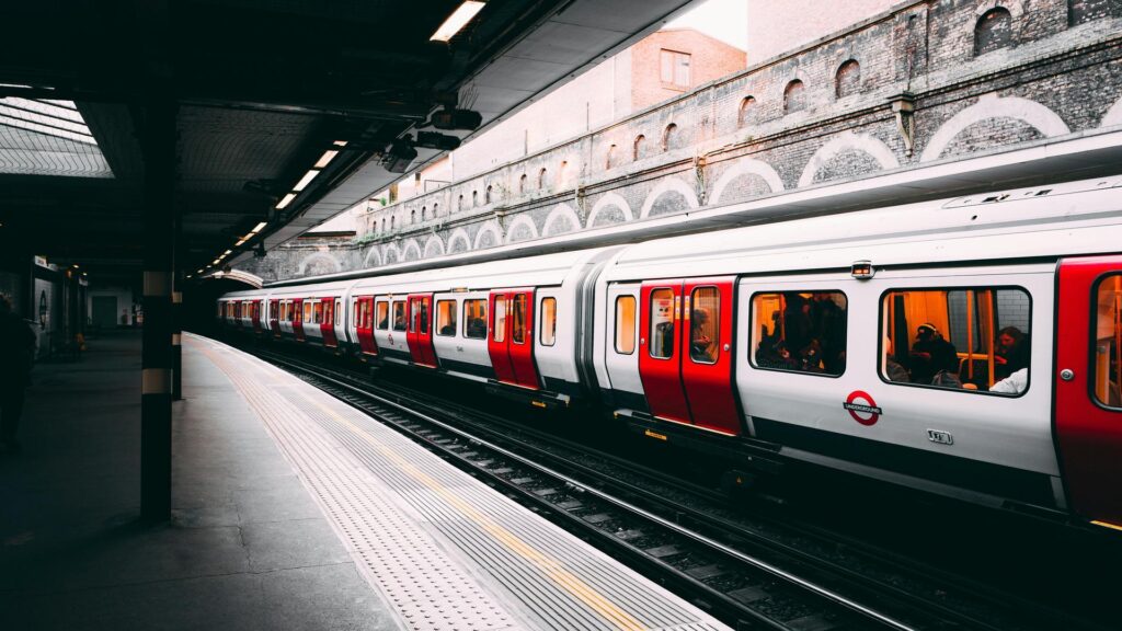 Red and white London Underground train car at a station platform with distinctive arched brick architecture