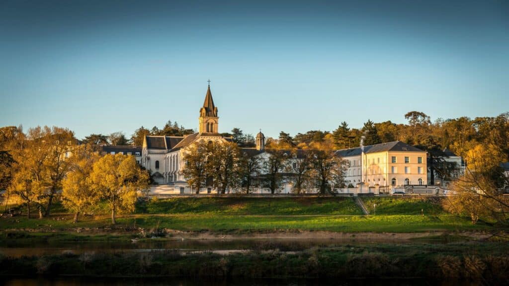 Panoramic view of Marmoutier Abbey complex with church spire and autumn trees along Loire River