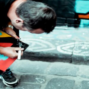 An artist working on vibrant street art with colorful designs on a London street.