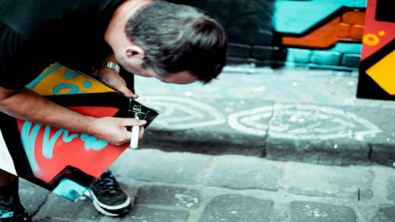 An artist working on vibrant street art with colorful designs on a London street.