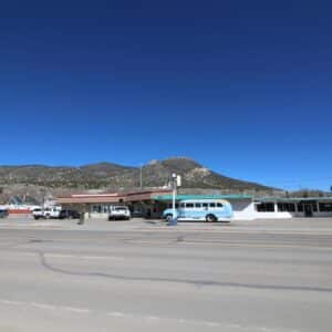 A roadside motel with a sign reading 'Silver State,' set against a backdrop of mountains under a clear blue sky.