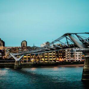 Places to visit in London: St Paul's Cathedral dome and Millennium Bridge over Thames River at dusk with illuminated buildings