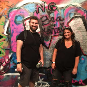 Two people enjoying London sightseeing with vibrant graffiti art in the background, showcasing unique London activities.