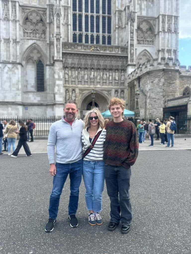 Family posing in front of Westminster Abbey during London sightseeing tours - Sites To See In London