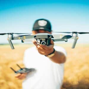 Person holding a DJI Mavic Pro drone in a wheat field against blue sky