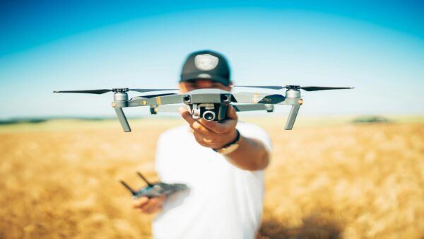 Person holding a DJI Mavic Pro drone in a wheat field against blue sky