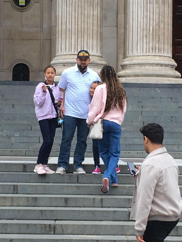 Visitors on the steps of a historic building in London, UK, enjoying sightseeing tours.