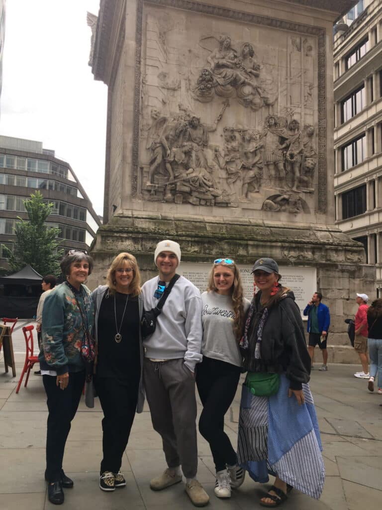 Group posing in front of the Monument to the Great Fire of London, a top sightseeing spot in London.