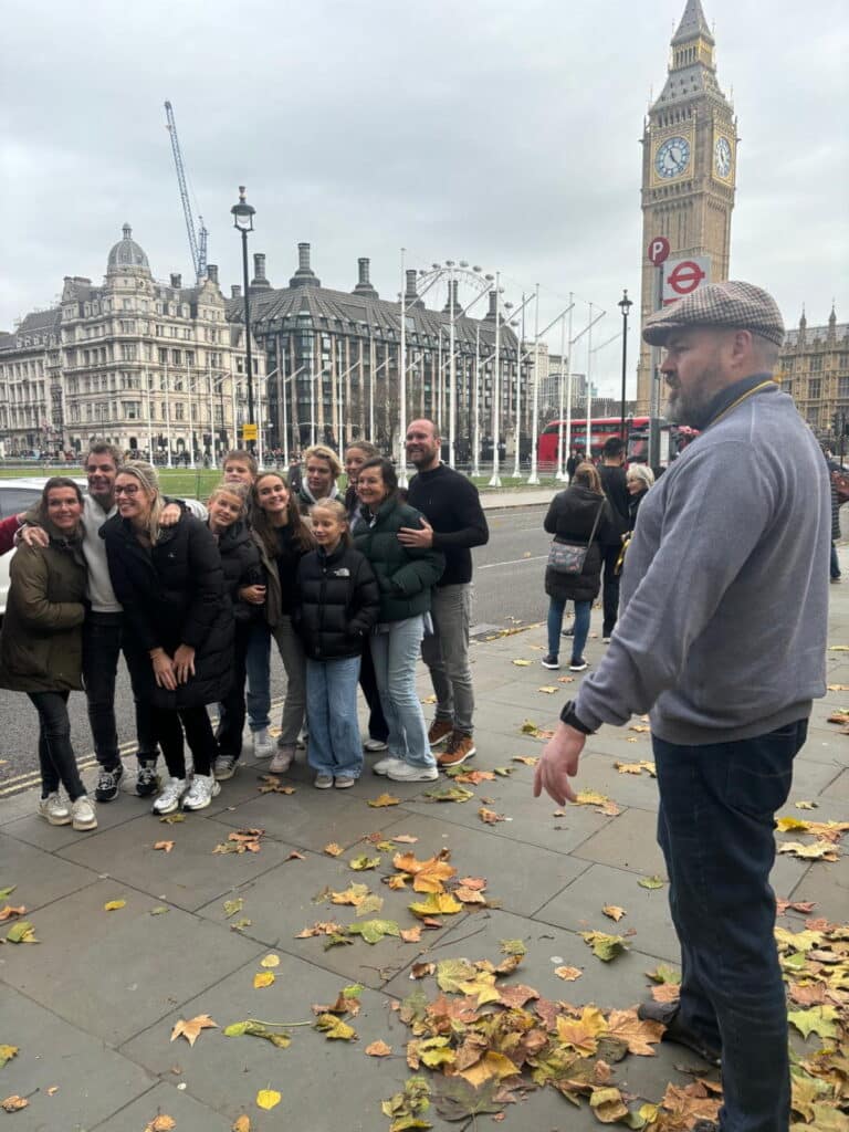 Group enjoying a London sightseeing tour near Big Ben, showcasing iconic landmarks and the London Eye in the background - Places To See In London UK