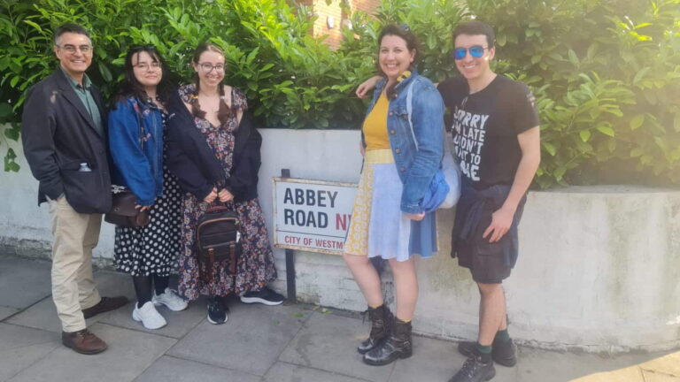 Group posing by the Abbey Road sign, a must-visit destination for London sightseeing taxi tours.