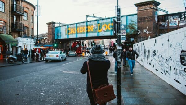 Person standing near Camden Lock railway bridge in London with vintage leather satchel