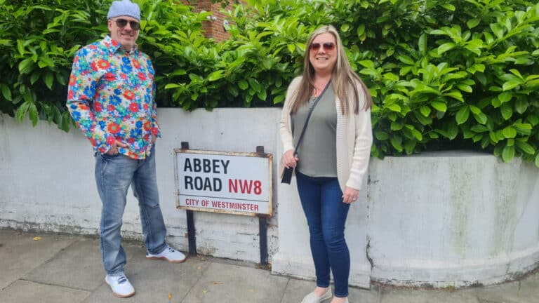 Tourists posing at Abbey Road sign, a famous London attraction, during a sightseeing taxi tour.