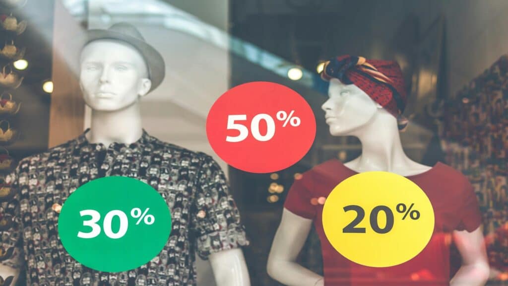 Store window display with two mannequins showing various percentage discounts - 50%, 30%, and 20% off