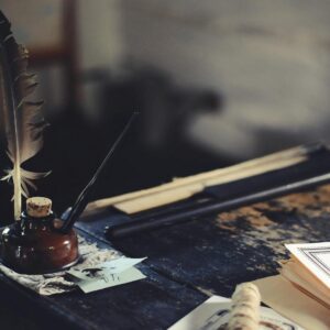 A quill and ink bottle on an old wooden desk