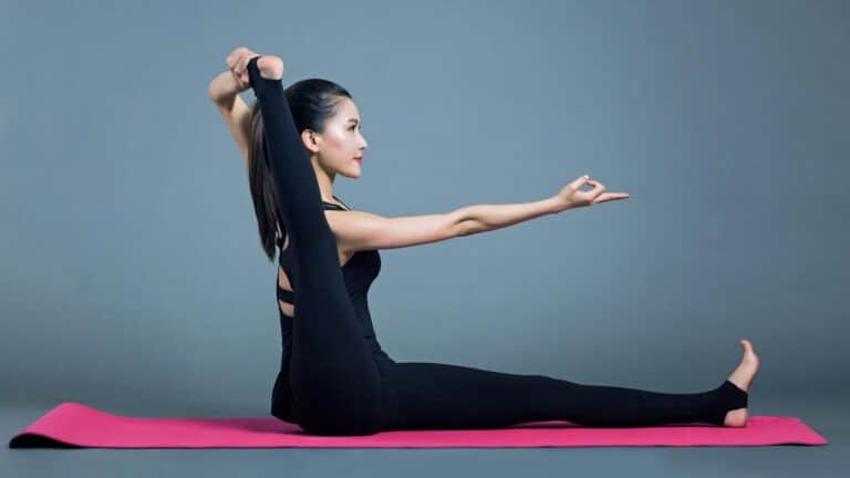 Person performing an advanced yoga pose on a pink mat