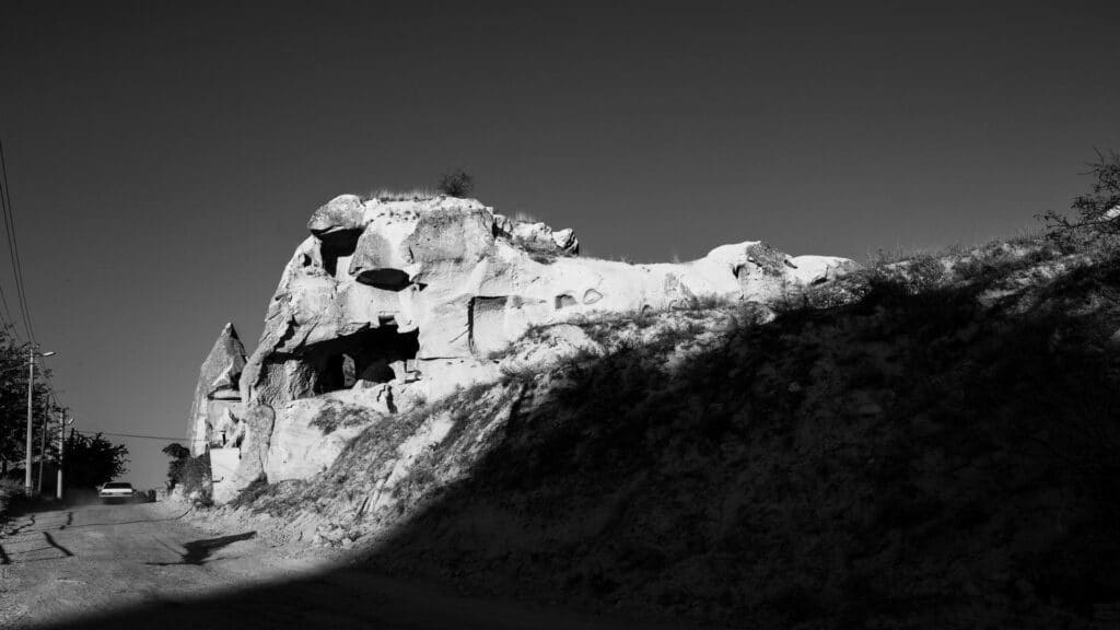 A rugged rock formation along a dirt road with shadows cast by the setting sun.