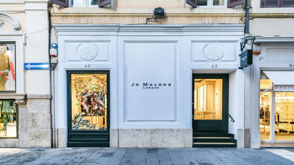 Elegant white facade of Jo Malone London store with numbers 42 and 43, featuring classic architectural details and illuminated window displays