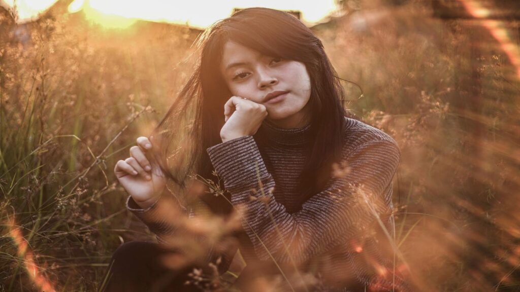 Woman sitting in a field during sunset