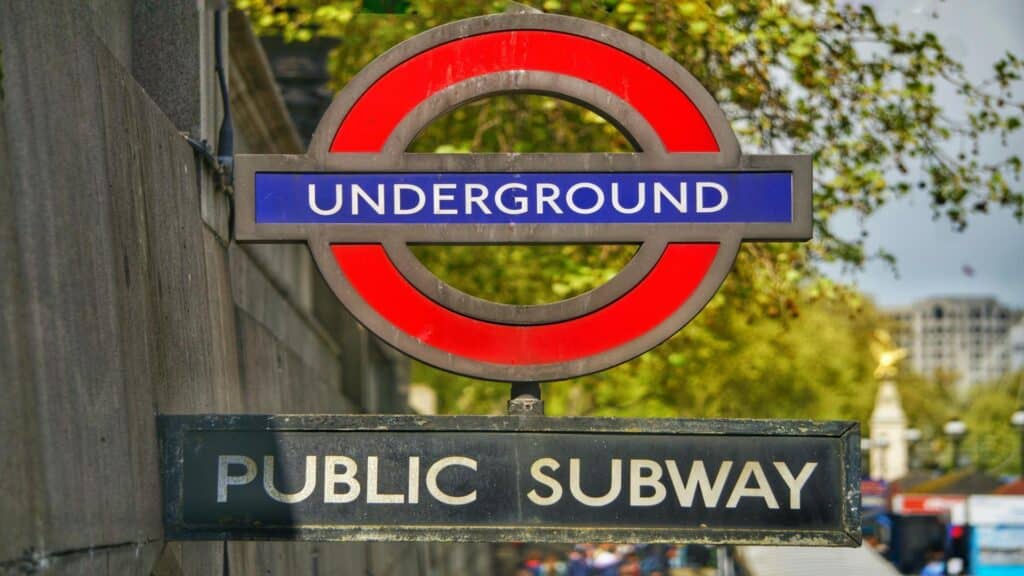 A London Underground sign with a red circle and blue rectangle, indicating a public subway entrance.