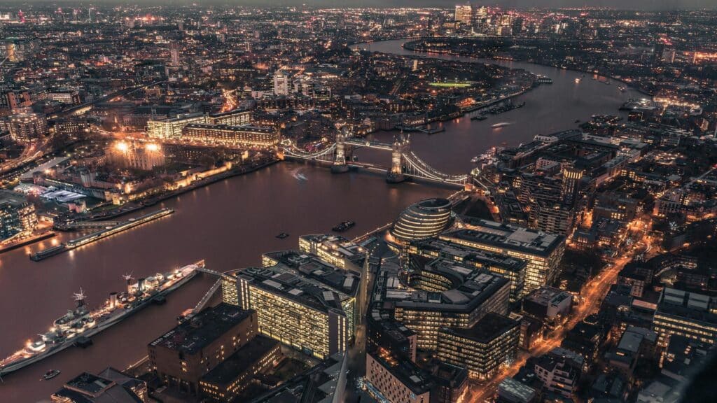 Aerial view of London at night featuring Tower Bridge and the River Thames.