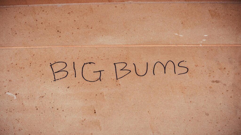 Graffiti text reading 'Big Bums' on a wall