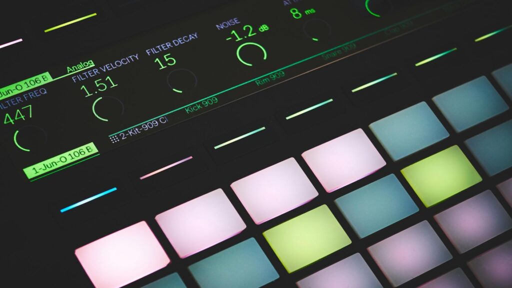 Close-up of a modern MIDI controller with illuminated pads and digital display showing audio parameters