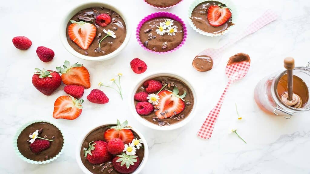 Bowls of chocolate dessert topped with strawberries, raspberries, and edible flowers.