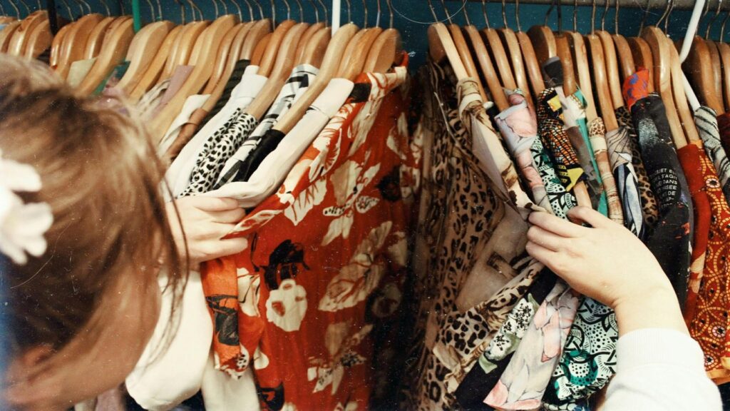 A person browsing colorful patterned clothing during exhibition tours.