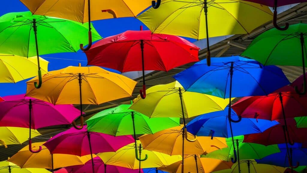 A vibrant arrangement of colorful umbrellas hanging against a blue sky