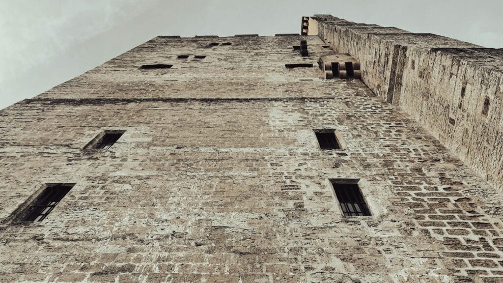 Upward view of a historic stone tower with small windows