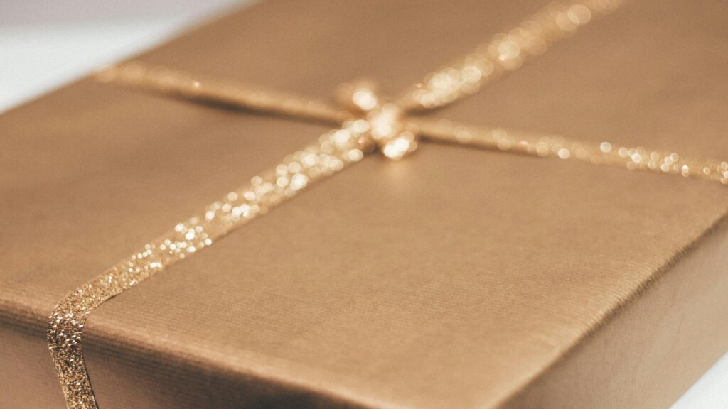 A close-up of a gold-wrapped gift box with a glittery ribbon.