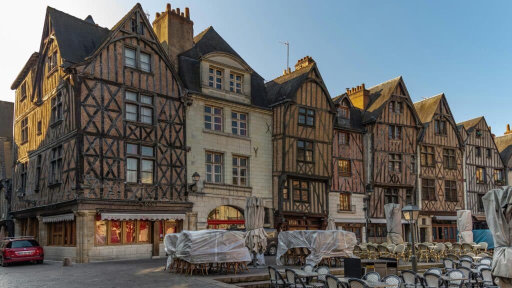 Row of historic half-timbered buildings in a European square during sunset.