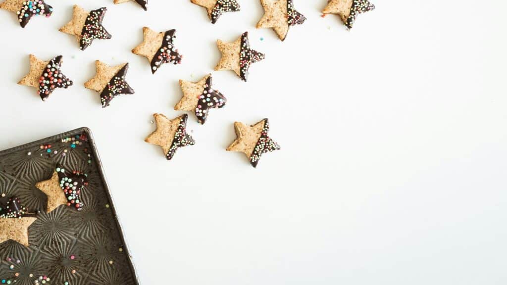 Star-shaped cookies dipped in chocolate and decorated with sprinkles on a white background.