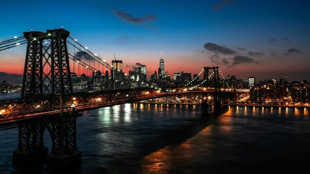 A bridge with a city skyline in the background during sunset