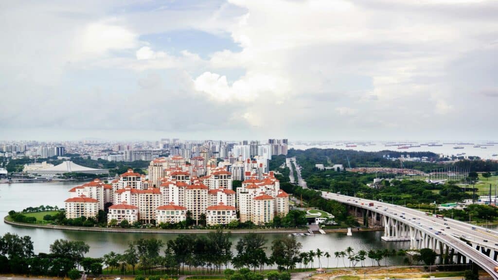 Aerial view of a waterfront area with residential buildings, a bridge, and ships in the background.