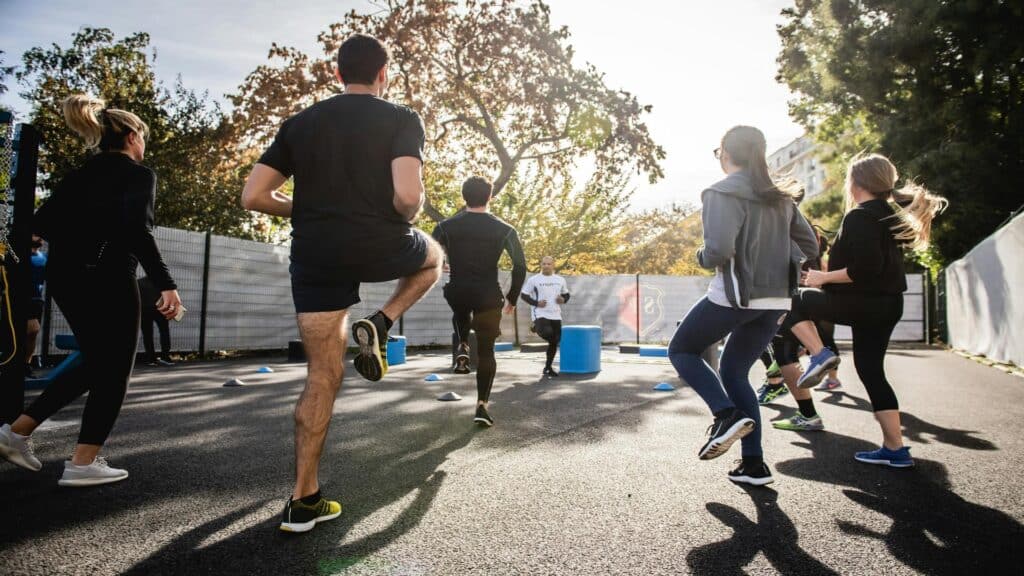 Group of people participating in an outdoor fitness class with exercise cones and equipment at sunset