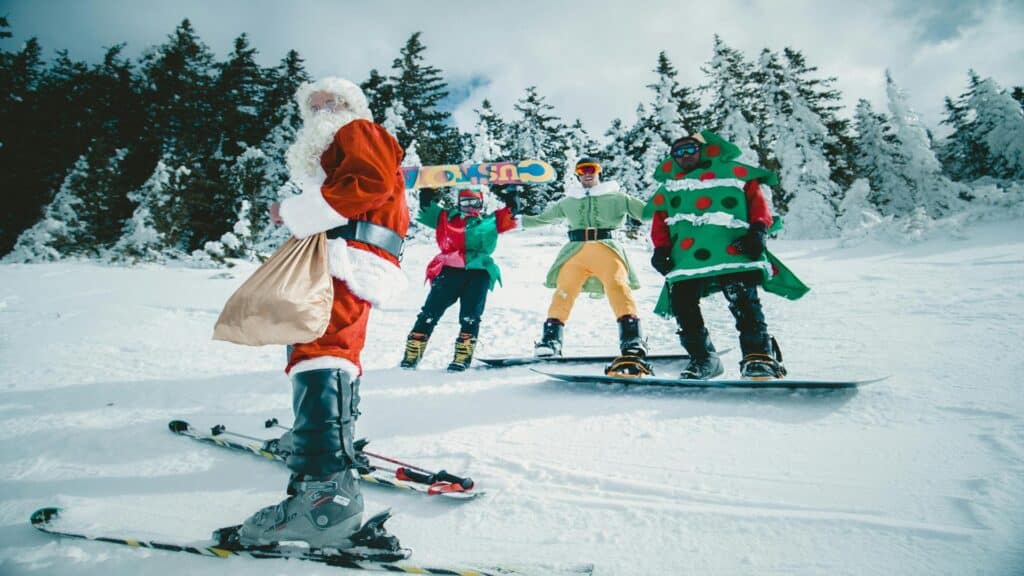 Group dressed in Christmas costumes skiing and snowboarding on a snowy slope.