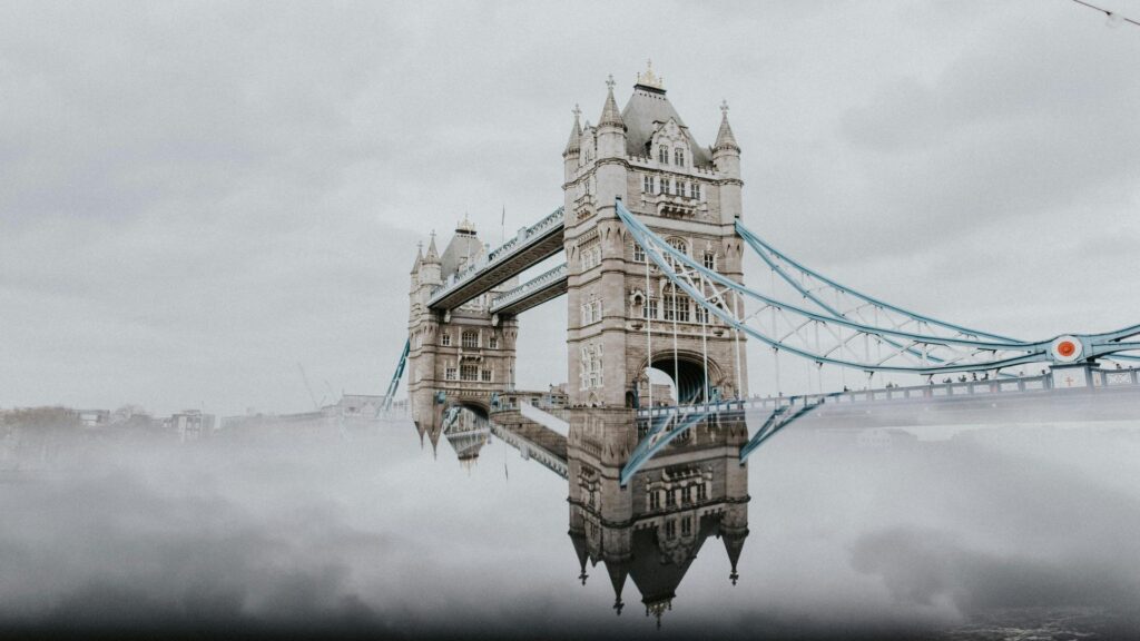 View of Tower Bridge in London with its reflection in water on a cloudy day