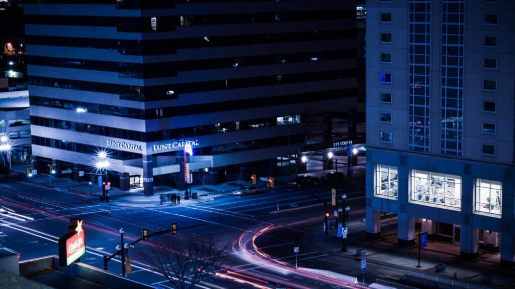 Long exposure nighttime cityscape showing Lunt Capital building with light trails from traffic and illuminated storefronts